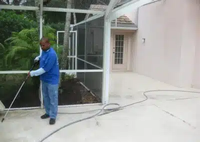 A man in blue shirt holding hose near tree.