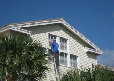 A man on a ladder cleaning the outside of a house.