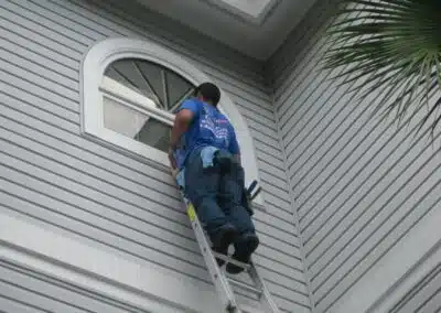 A man on a ladder cleaning the outside of a house.
