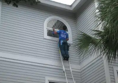 A man on a ladder cleaning the outside of a house.