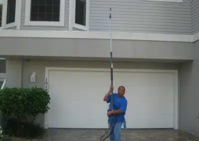 A man holding a pole in front of a house.