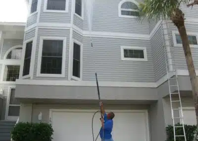 A man holding a hose and a pole outside of a house.