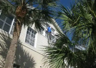 A man is on the side of a building while hanging from a ladder.